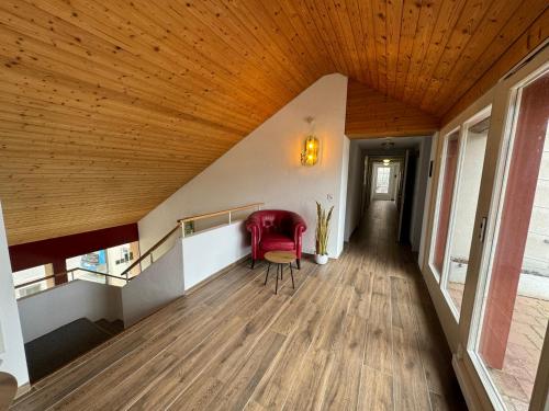a hallway with a red chair and a wooden ceiling at Lake View Double Room in Därligen