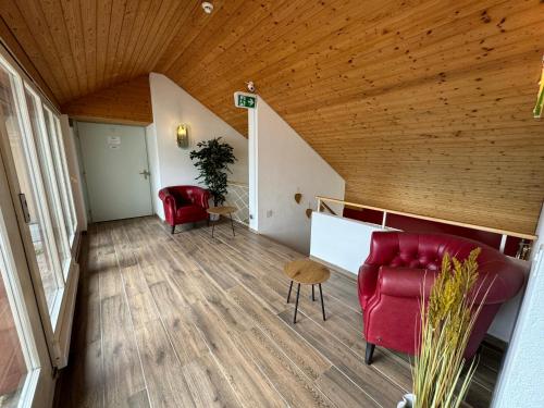 a living room with red chairs and a wooden ceiling at Lake View Double Room in Därligen