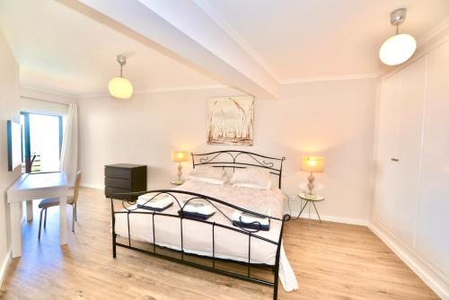 a bedroom with a bed and a desk and a window at Palm Tree in São Martinho do Porto