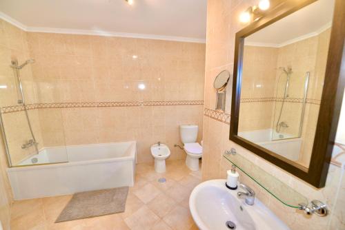 a bathroom with a tub and a sink and a toilet at Palm Tree in São Martinho do Porto