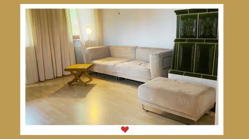 a living room with a white couch and a table at Berghupferl-Alm - do legst di nieda in Flintsbach am Inn