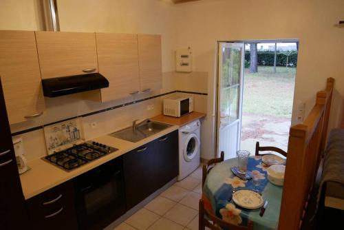 une cuisine avec une table, un évier et une cuisinière dans l'établissement La Petite maison de pays, à Saint-Hilaire-de-Riez