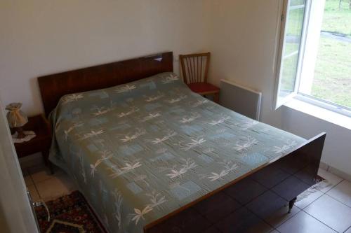 ein Schlafzimmer mit einem Bett mit blauer Bettdecke und einem Fenster in der Unterkunft La Grande maison de pays in Saint-Hilaire-de-Riez