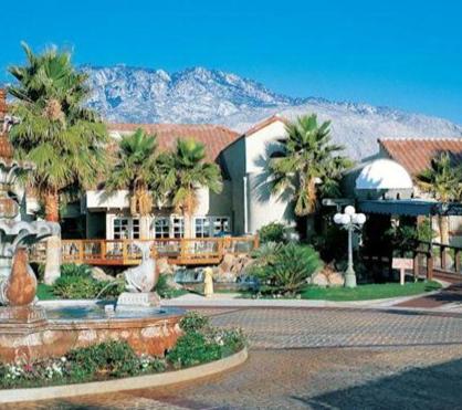 a house with palm trees in front of a mountain at The Oasis Resort in Palm Springs