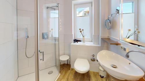 a white bathroom with a sink and a shower at 54° Nord Wohnung 3 in Grömitz