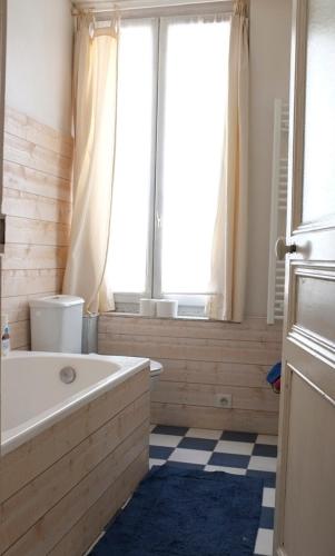 une salle de bain avec une baignoire et une fenêtre dans l'établissement Charmante Maison de Pêcheur à Trouville sur Mer, à Trouville-sur-Mer