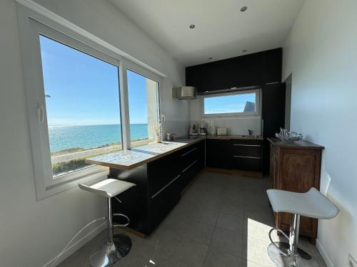 une cuisine avec vue sur l'océan depuis une fenêtre dans l'établissement Villa Denise Grand Gîte, à Barneville-Carteret
