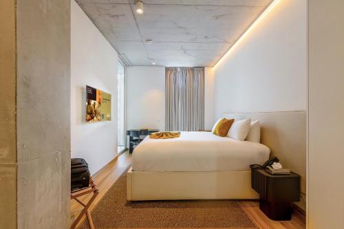 1 dormitorio con 1 cama blanca grande en una habitación en ONOMO ALLURE ABIDJAN BAOBAB, en Abiyán