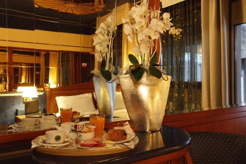 a table with a plate of food and a vase of flowers at Hotel City Legnano in Legnano