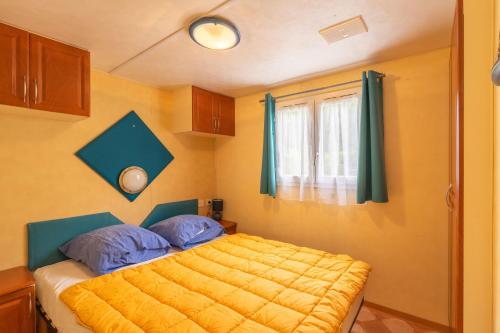 1 dormitorio con 1 cama con sábanas amarillas y ventana en Mobilhome Mh 212, en La Tremblade