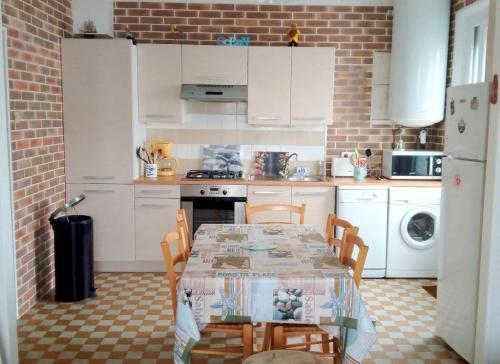 une cuisine avec une table et des chaises dans une cuisine dans l'établissement La Berardiere du centre, à Saint-Hilaire-de-Riez
