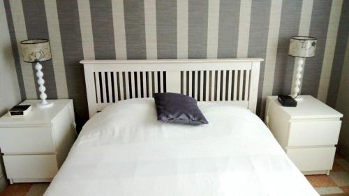 une chambre avec un lit blanc avec un oreiller dessus dans l'établissement La Berardiere du centre, à Saint-Hilaire-de-Riez