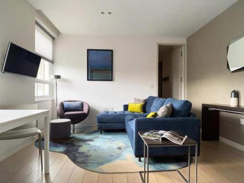 a living room with a blue couch and a table at Wells Court by Aeria Apartments in London