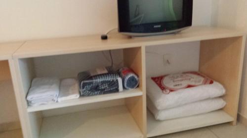 TV en la parte superior de un estante con toallas en Flat Particular em Ponta Negra, en Natal