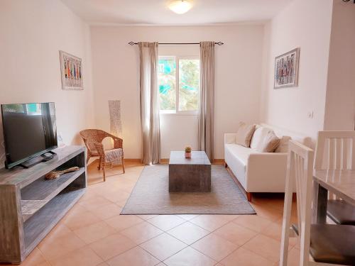 a living room with a white couch and a tv at Branco Sea Holiday Apartments in Santa Maria