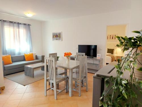 a living room with a table and chairs and a couch at Branco Sea Holiday Apartments in Santa Maria