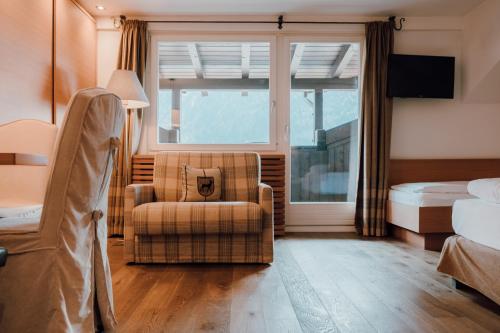 a bedroom with a chair and a bed and a window at Residence Hotel Alpinum in Campo Tures