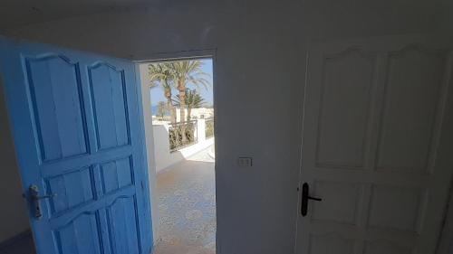 an open blue door in a room with a palm tree at Maison de sirène in Zarzis