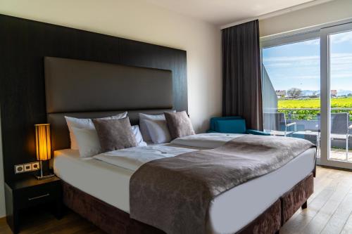 a bedroom with a large bed with a large window at Bodensee-Hotel Sonnenhof in Kressbronn am Bodensee