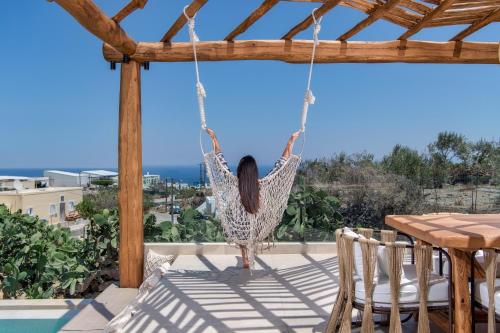 a woman is sitting in a hammock on a patio at Ayama Hideaway Private Villa in Fira
