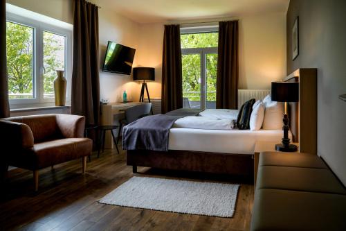 a bedroom with a bed and a chair and a window at Bodensee-Hotel Sonnenhof in Kressbronn am Bodensee