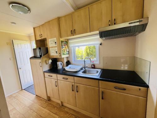 eine kleine Küche mit einem Waschbecken und einem Fenster in der Unterkunft KD 866 - Vakantiepark Kijkduin in Den Haag