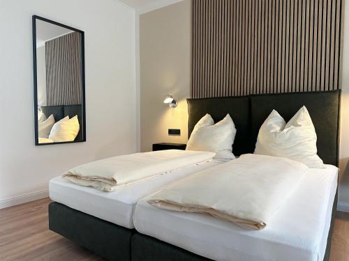 2 bedden in een hotelkamer met een spiegel bij Weingut Pieper - Vinothek & Hotel am Drachenfels in Bad Honnef am Rhein