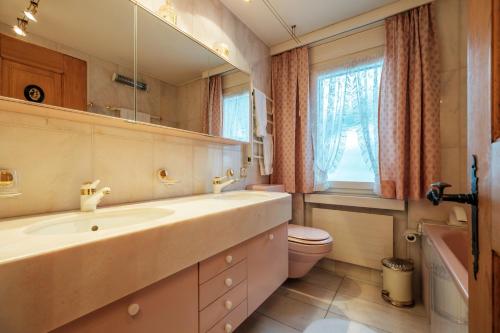 ダボスにあるHeart of Davos apartmentsのバスルーム(洗面台、トイレ、鏡付)