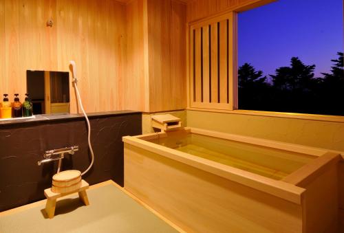 a bath tub in a bathroom with a window at 伊豆高原の隠れ宿Syuhari守破離 in Ito