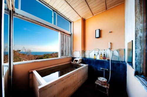 a bathroom with a tub with a large window at 伊豆高原の隠れ宿Syuhari守破離 in Ito