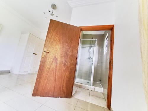 - Puerta de madera en el baño con ducha en Beautiful one bed apartment in Tema Community 6, en Tema