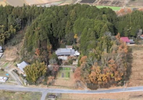 an aerial view of a house on a hill with trees at 古民家やまおか in Iwasaki