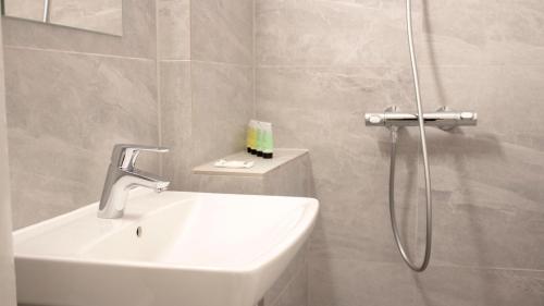 a white bathroom with a sink and a shower at A Hotels Apartments Høje Taastrup in Tåstrup