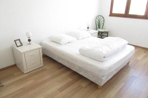 un lit avec des draps blancs et des oreillers dans une chambre dans l'établissement Le face mer de la Corniche Vendéenne, à Saint-Hilaire-de-Riez