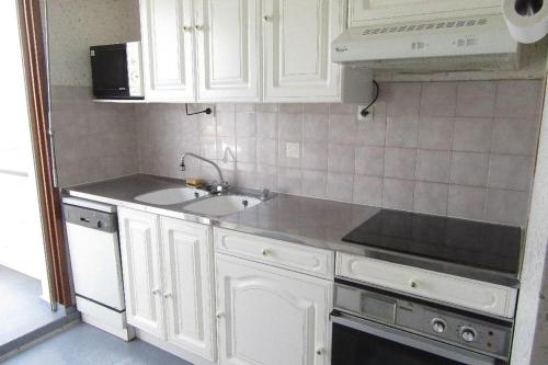 une cuisine avec des armoires blanches et un évier dans l'établissement Le face mer de la Corniche Vendéenne, à Saint-Hilaire-de-Riez