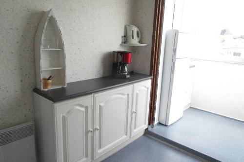 La cuisine est équipée d'une armoire blanche et d'un réfrigérateur. dans l'établissement Le face mer de la Corniche Vendéenne, à Saint-Hilaire-de-Riez