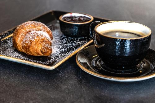 a plate with a pastry and a cup of coffee at Bodensee-Hotel Sonnenhof in Kressbronn am Bodensee