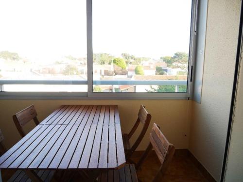 - une table et des chaises en bois dans une chambre avec fenêtre dans l'établissement Le studio de la corniche, à Saint-Hilaire-de-Riez
