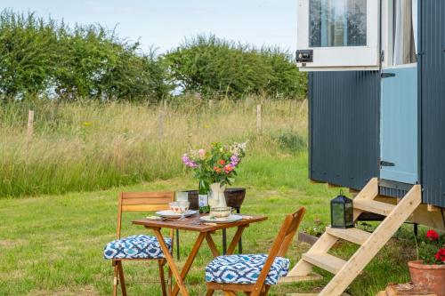 a table with two chairs and a table with flowers on it at Saltmarsh Hut in Stiffkey