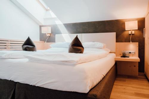 a bedroom with two beds with white sheets at Residence Hotel Alpinum in Campo Tures