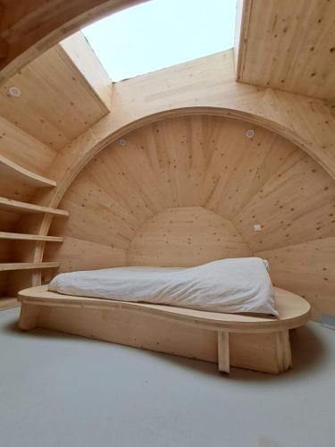 een rond bed in een houten kamer met een trap bij Les chaumières de Brameix in Neuvic