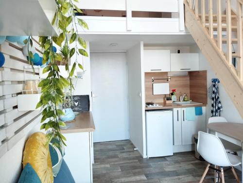 une petite cuisine avec des placards blancs et un escalier dans l'établissement Le cosy de la corniche d'or, à Saint-Hilaire-de-Riez
