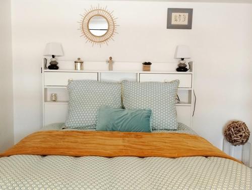 une chambre avec un lit avec deux oreillers et un miroir dans l'établissement Le cosy de la corniche d'or, à Saint-Hilaire-de-Riez
