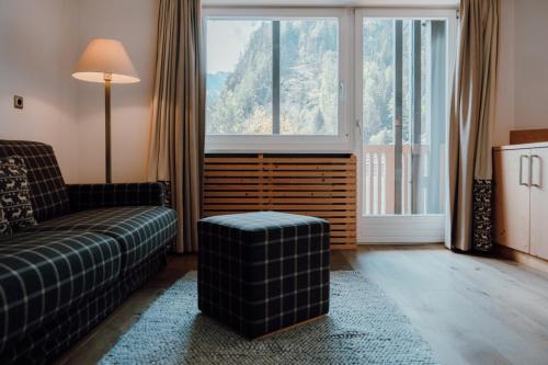 a living room with a couch and a large window at Residence Hotel Alpinum in Campo Tures