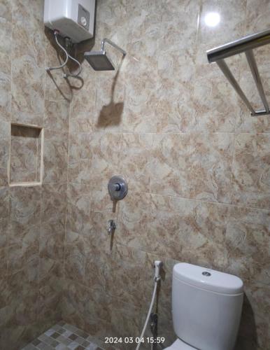 a bathroom with a toilet and a stone wall at Karjo Homestay Syariah in Ngadipuro