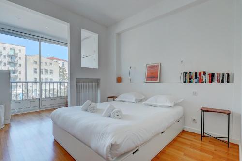 - une chambre blanche avec un grand lit et une grande fenêtre dans l'établissement Bella Vista - Appt avec vue sur le Vieux Port, à Marseille