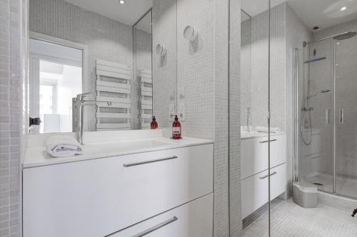une salle de bain blanche avec un lavabo et une douche dans l'établissement Bella Vista - Appt avec vue sur le Vieux Port, à Marseille