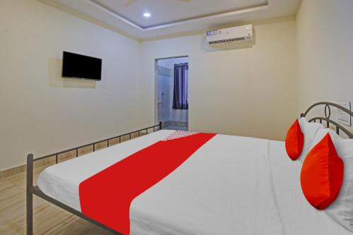 een slaapkamer met een bed met rode kussens en een televisie bij OYO Flagship Hotel Vathsalya in Warangal
