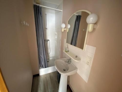 une salle de bain blanche avec un lavabo et un miroir dans l'établissement La croix de Vie du Boisvinet, à Saint-Gilles-Croix-de-Vie