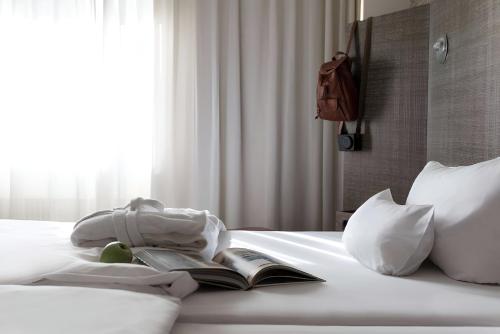 a bedroom with a bed with a book and pillows at pentahotel Vienna in Vienna